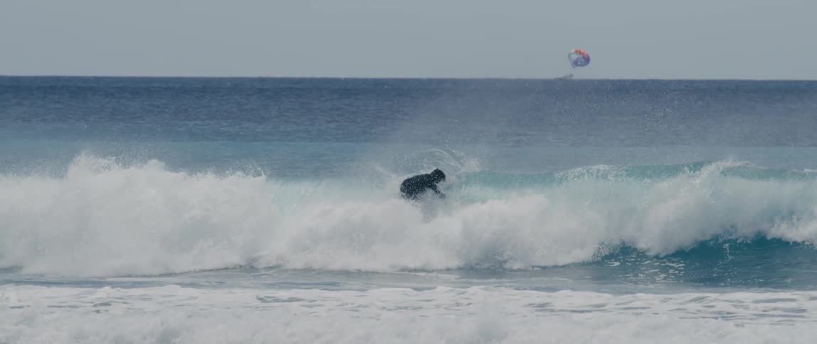 A surfer twirls in midair while riding a foaming curling breaking wave