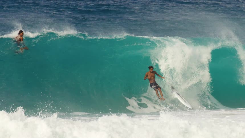 A man falls off his surfboard while riding a wave