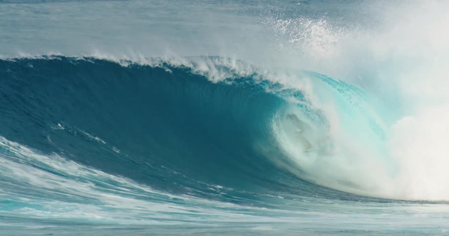 People are wearing wet suits and surfing a large wave in the ocean