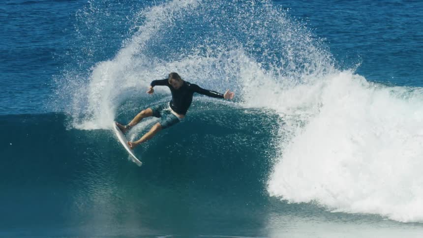 Young man riding a surfboard over a big waves in the ocean