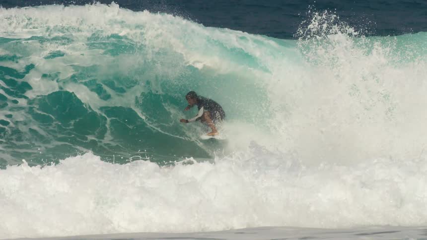 Male surfer with wetsuit and shorts rides big ocean wave