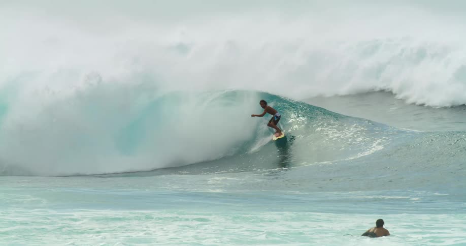 Young man riding a yellow surfboard on the big waves in the ocean
