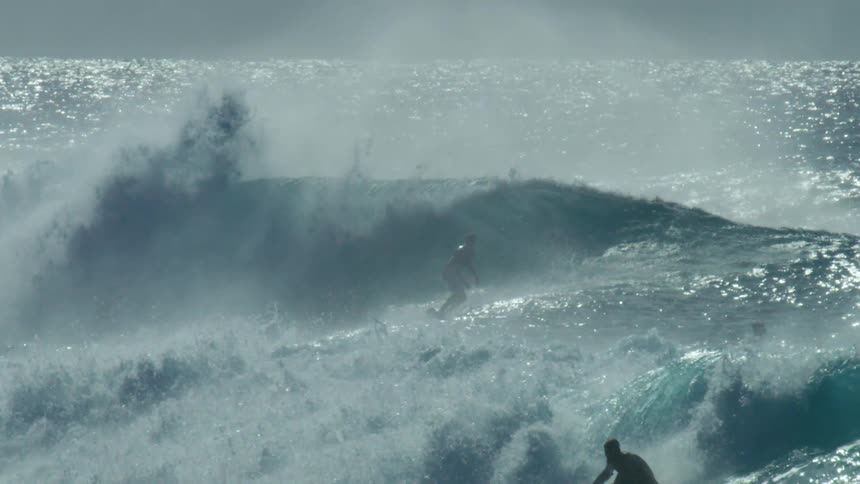 A man surfs before a tall wave on the ocean on a sunny day