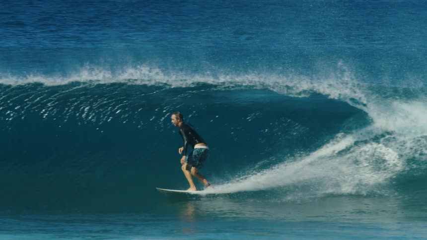 A large wave knocks a surfer off his surfboard