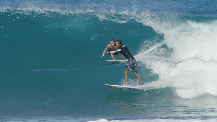 Four men surf on large waves in the ocean