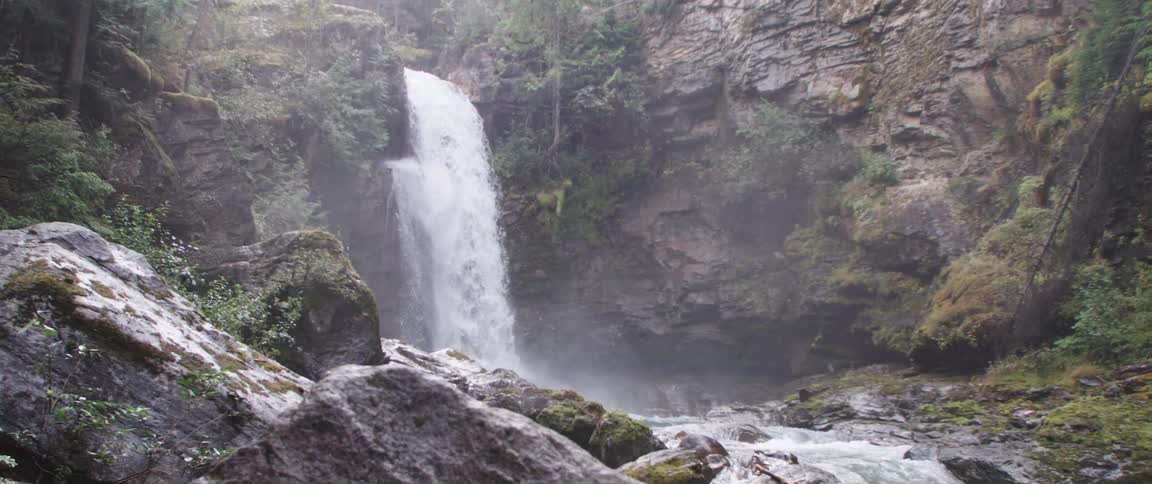 Waterfall cascades down cliffside in the forest