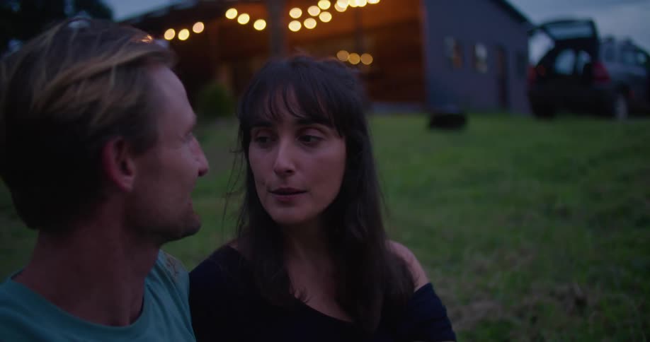 A man and woman talk while sitting outside