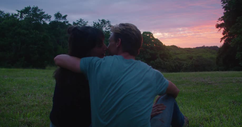 A man wraps his arm around a woman sitting in a rural lawn