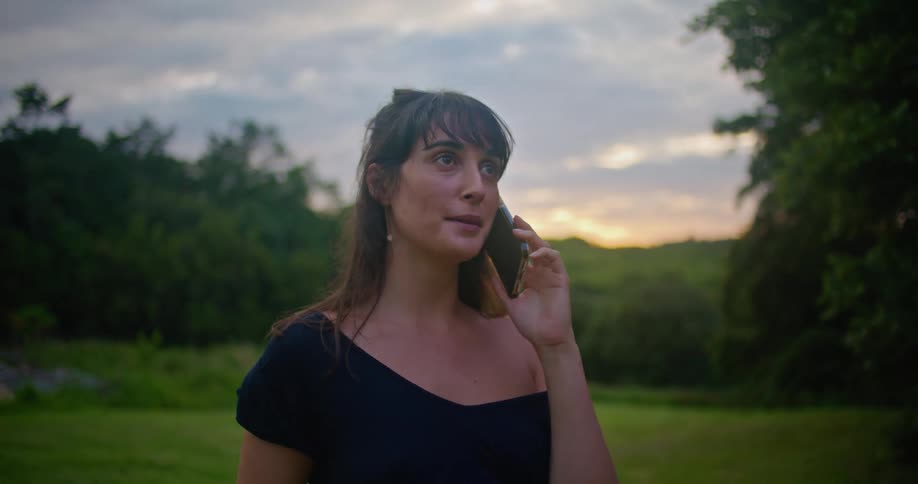 A woman stands in a rural lawn talking on a phone