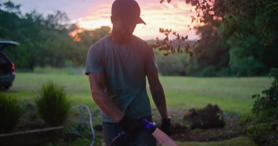 A man watering grass outdoors