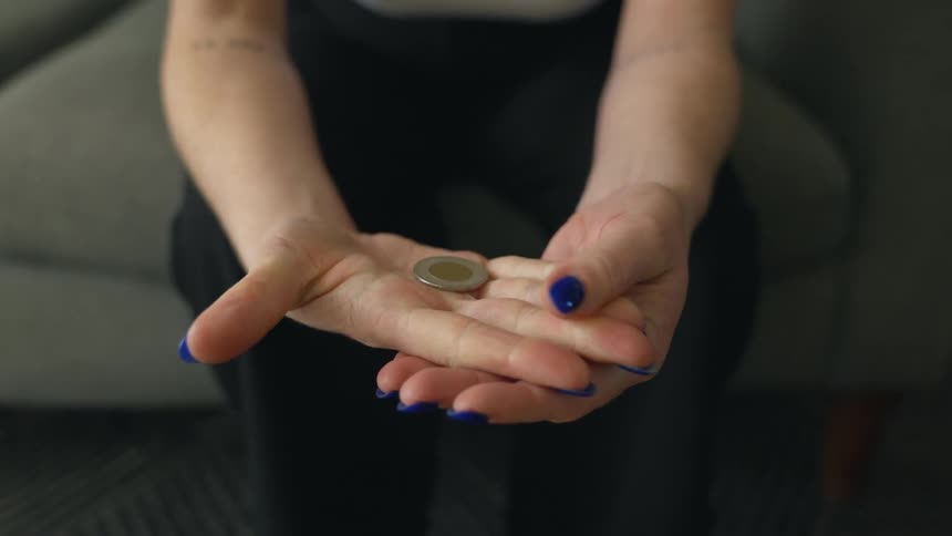 A woman with painted fingernails holding a coin in her hands