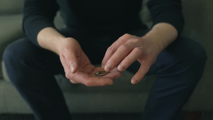 A man is touching the coin in his hand
