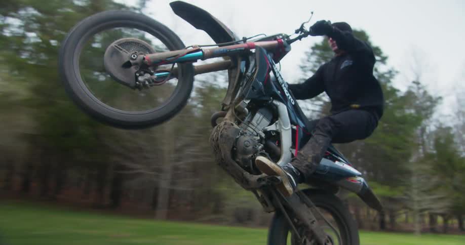A man is riding a motorcycle on a street and doing a wheelie