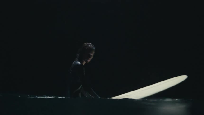 A surfer floating on a surfboard in the ocean at night