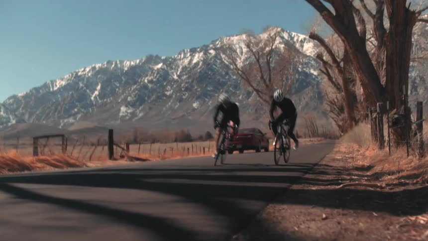 Two men wait a vehicle to pass before taking off on their bicycles