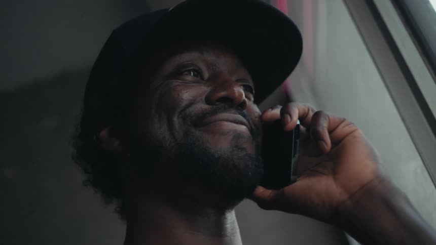 A man smiles while listened to his smartphone indoors during the day