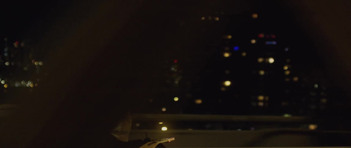 Motorcyclist rides motorbike along highway with city lit by lights in the background