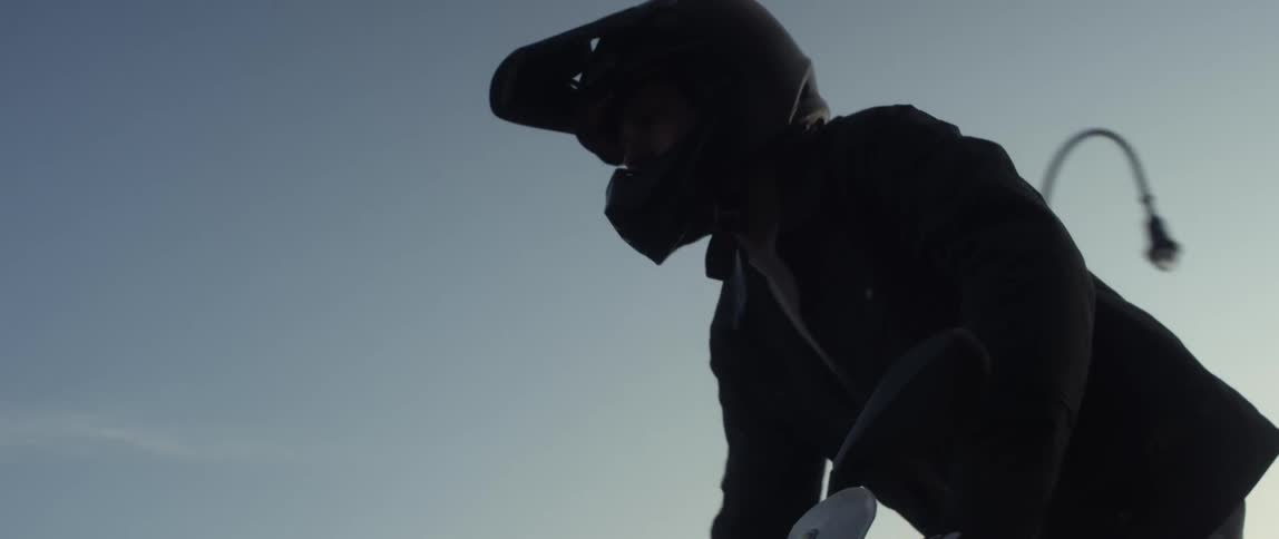 A man stands up while riding on his motorcycle