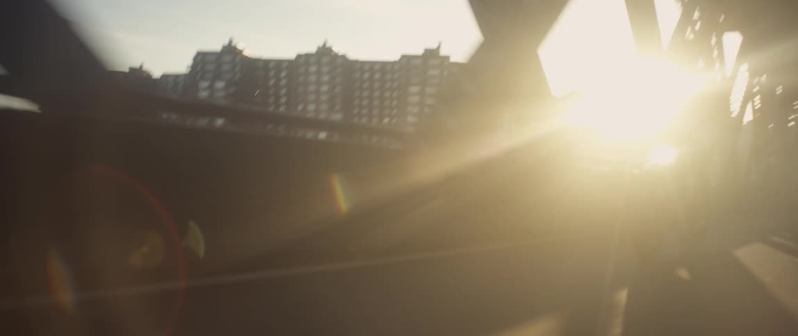 A man driving his motorcycle across a bridge stands up while driving