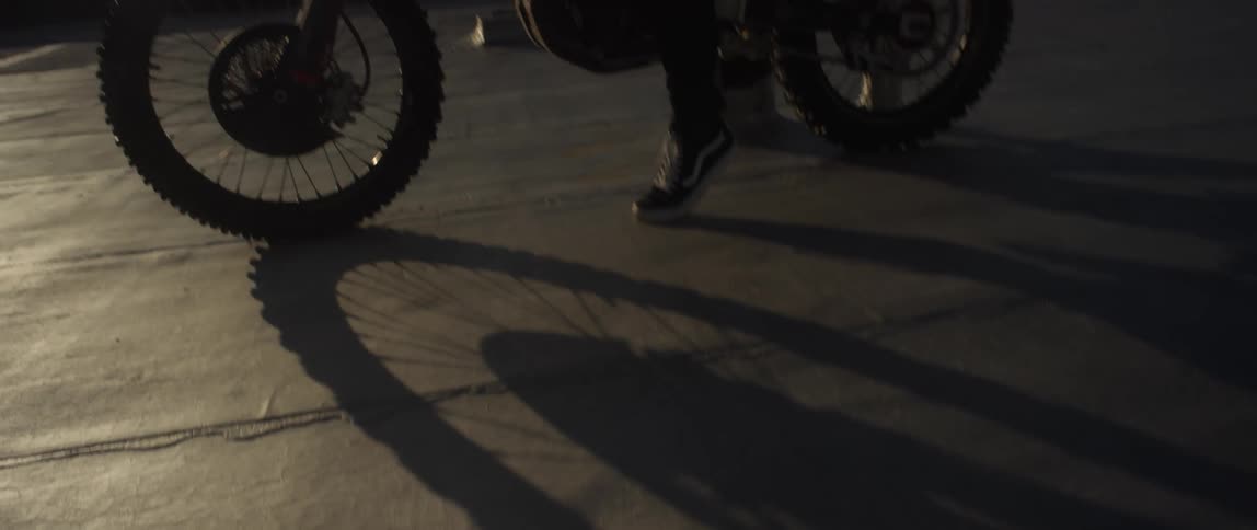 A person is sitting on a bike in the street at dusk