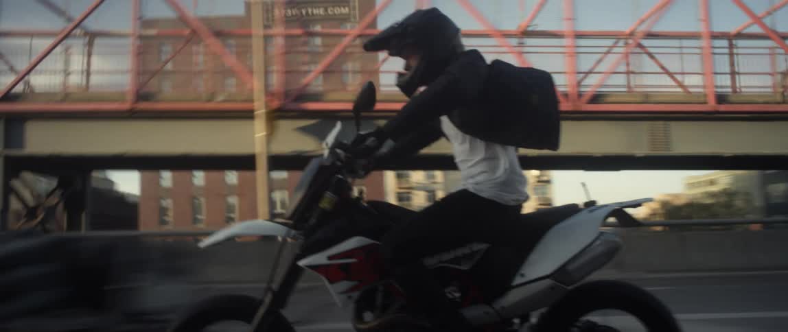 Young man wearing a black crash helmet rides a fast motorcycle over a bridge on the city