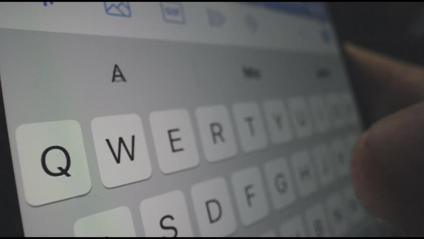 A person it typing on a cell phone keyboard with their thumb