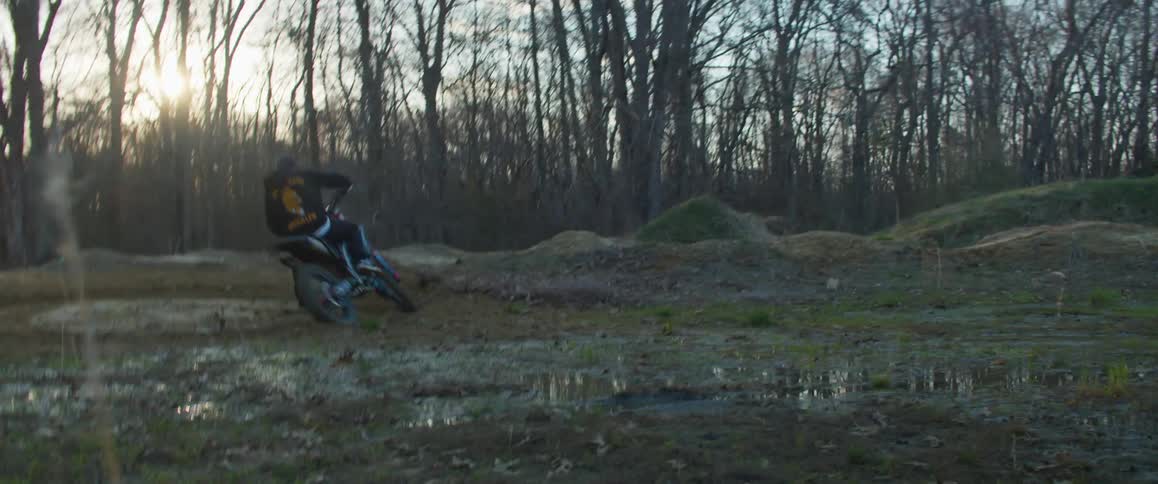 A man is riding a motorcyle at dusk in winter