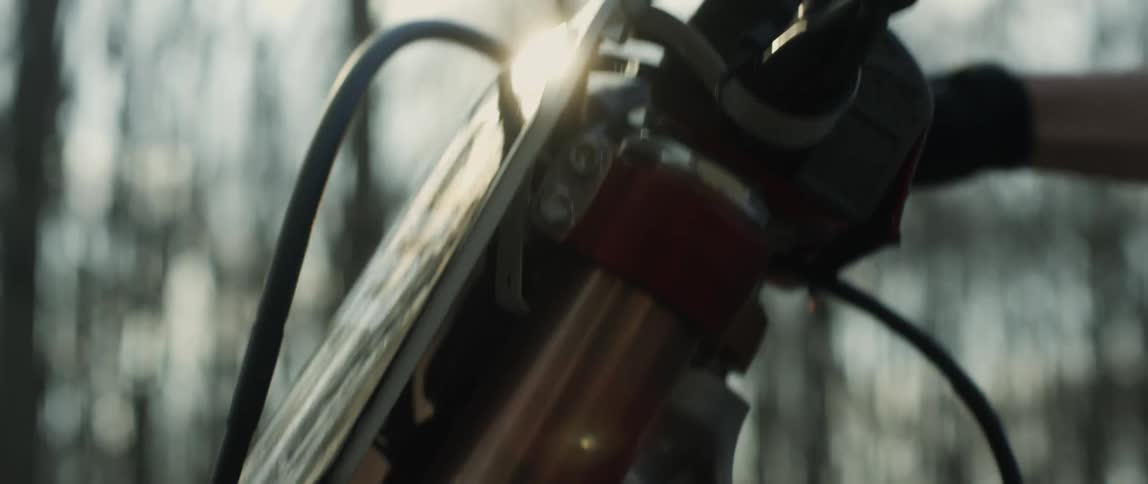 Man sitting on motorcycle near leafless trees revs the engine with the ignition bar