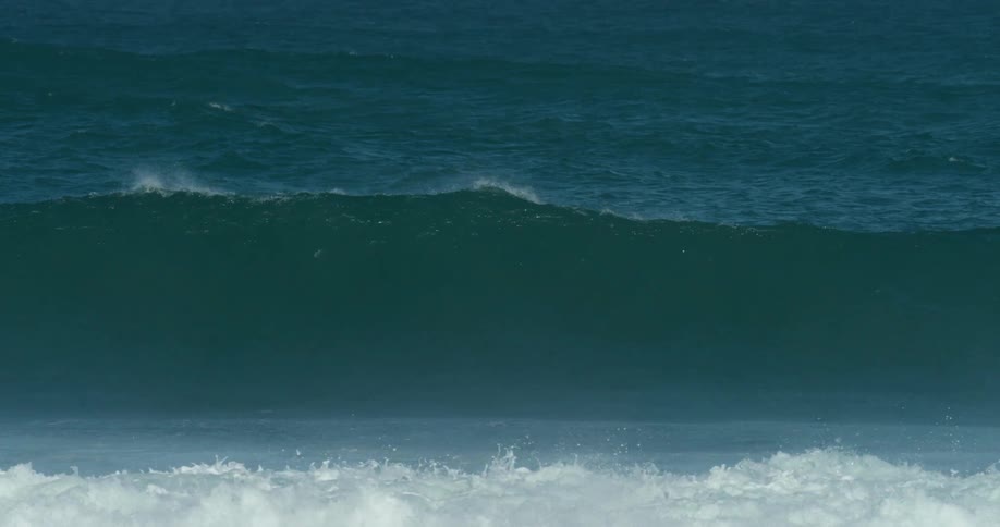 A surfer lying on his surfboard rides over a wave