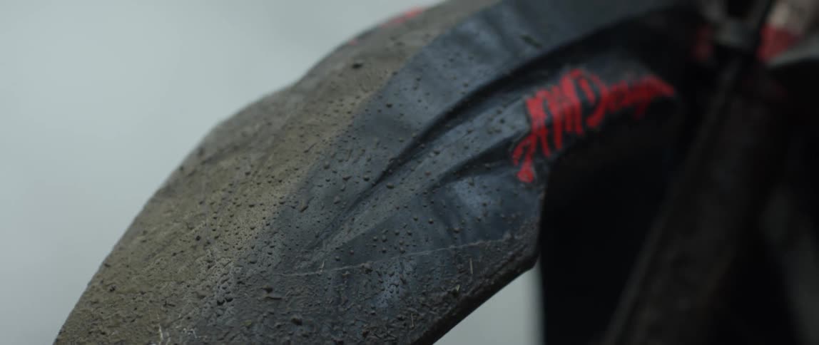 Close up of the black dirty fender of a motorcycle surrounded by white smoke