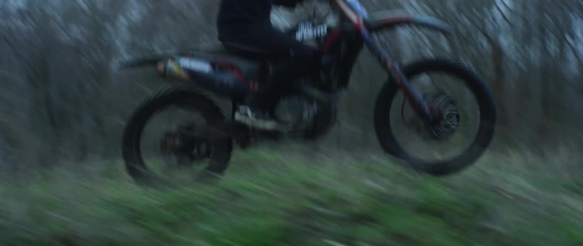 Young man rides a motorcycle on the slopes and hills near the forest