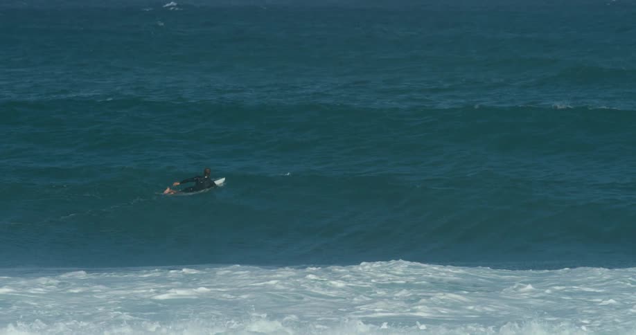 A person is surfing on ocean waves at midday