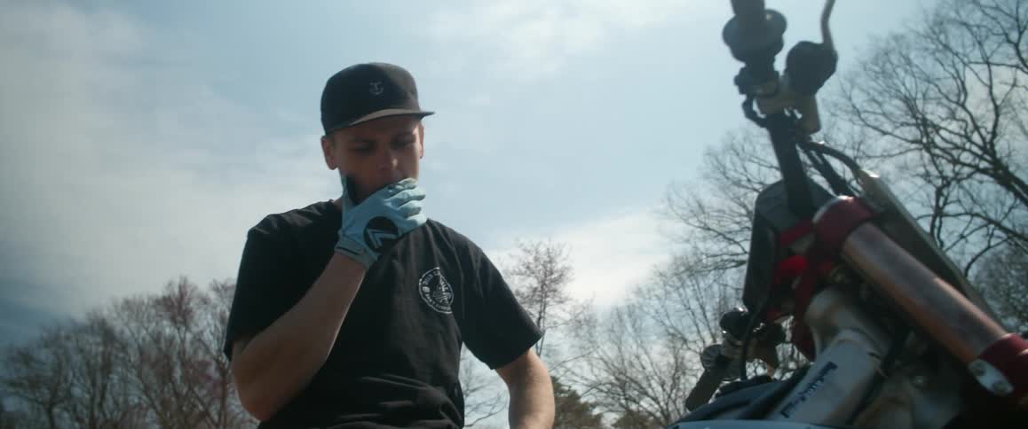A man is looking down examining his dirt bike