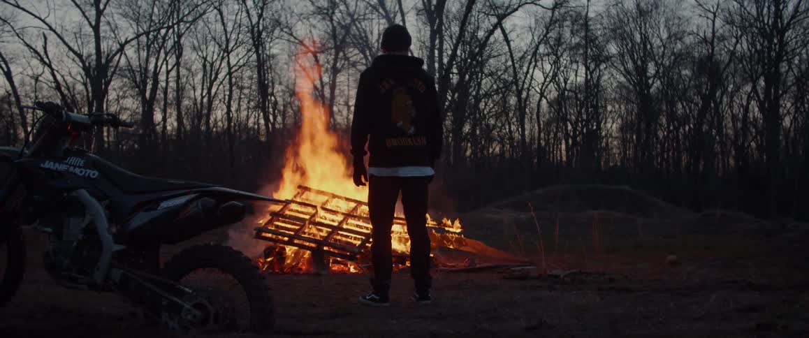 A man stands by the bonfire at sunset