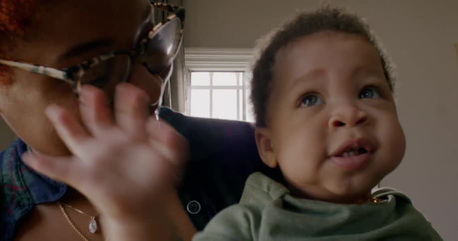 A mom holds her little boy and smiles lovingly at his chubby cheeks