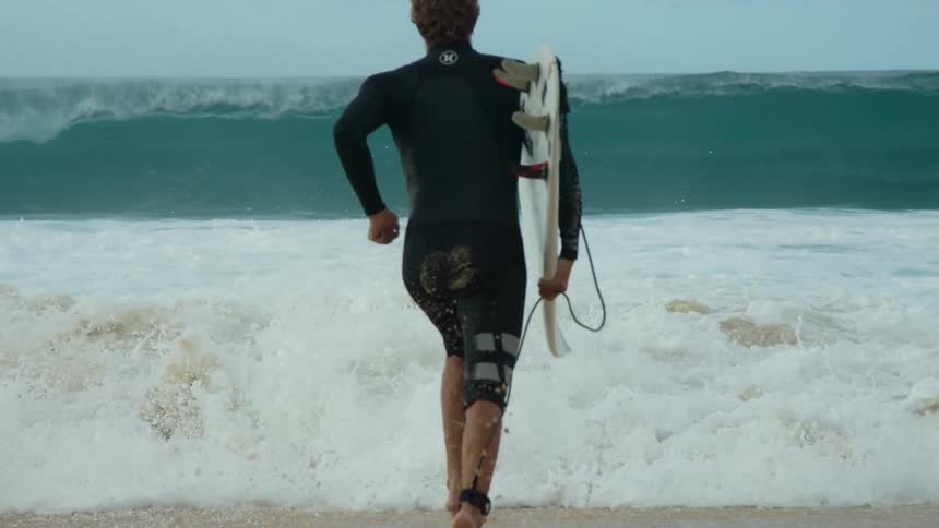 Surfer running into water