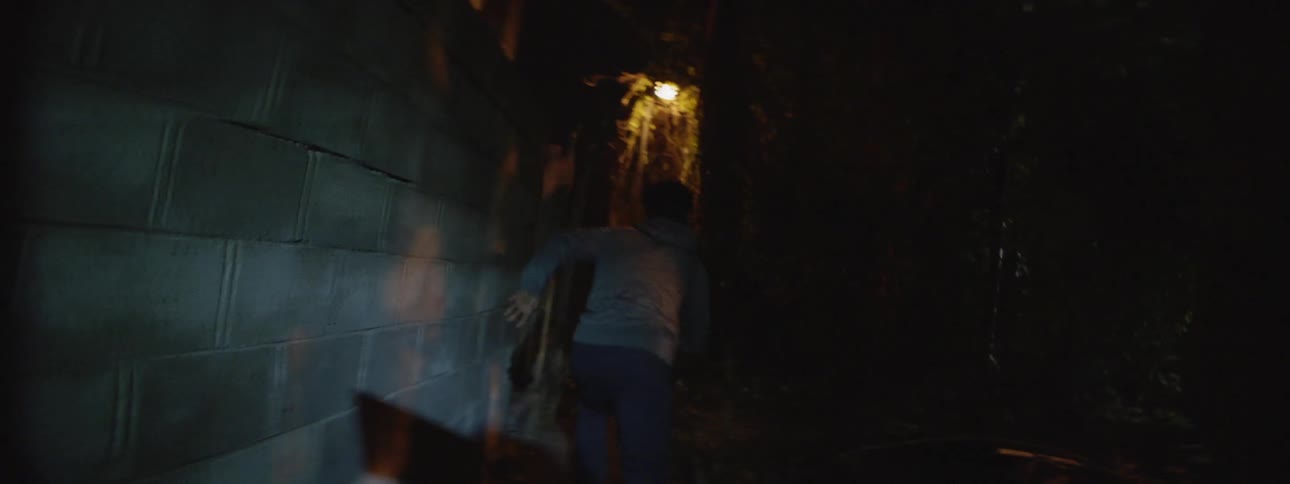 A man rushes through a dark alley
