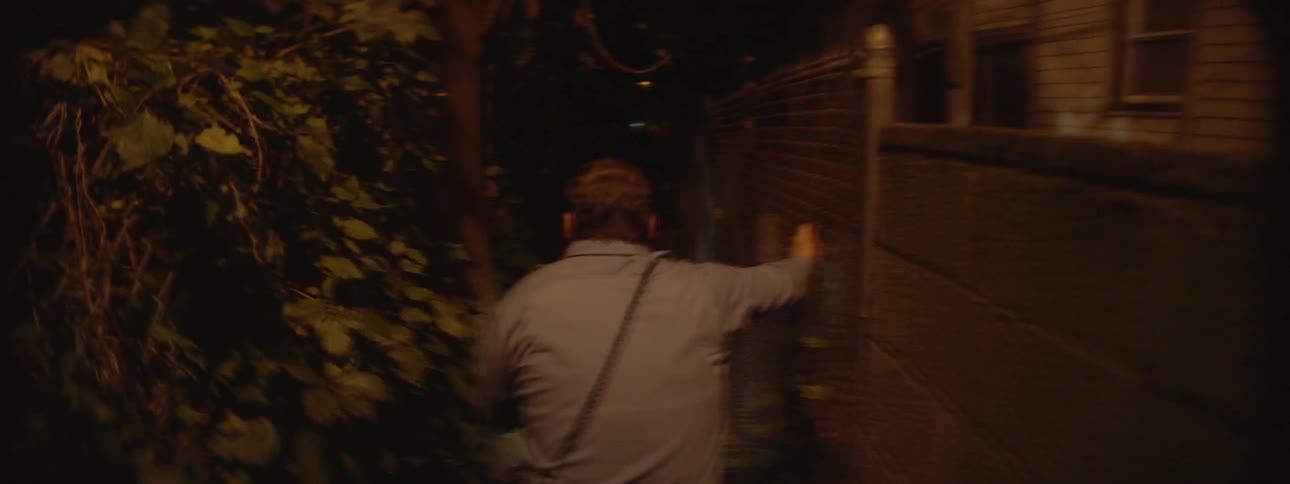 A police officer runs down a dark alley