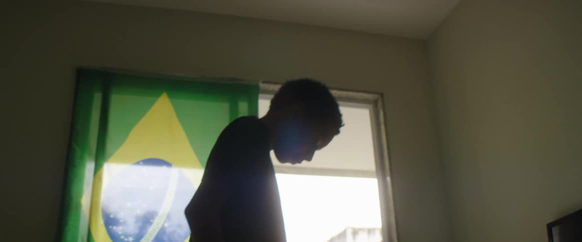 A teenage boy is moving a soccer ball around with his feet inside a house