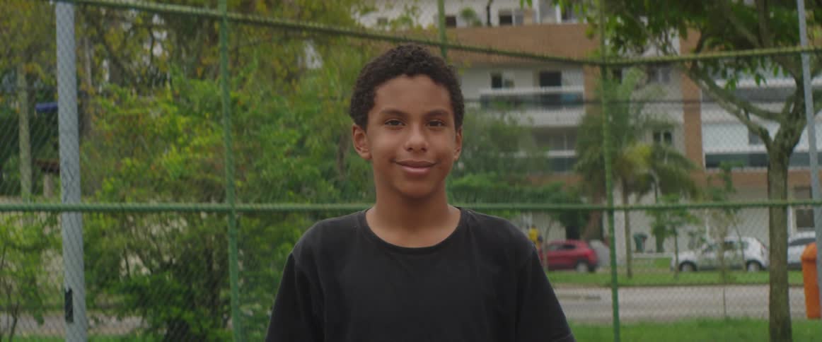 Happy boy with black t shirt smiles at camera in astroturf pitch