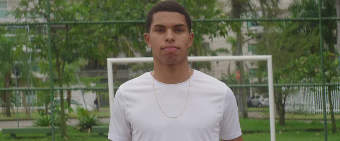 A young male stands on a soccer field passing the ball in his hands