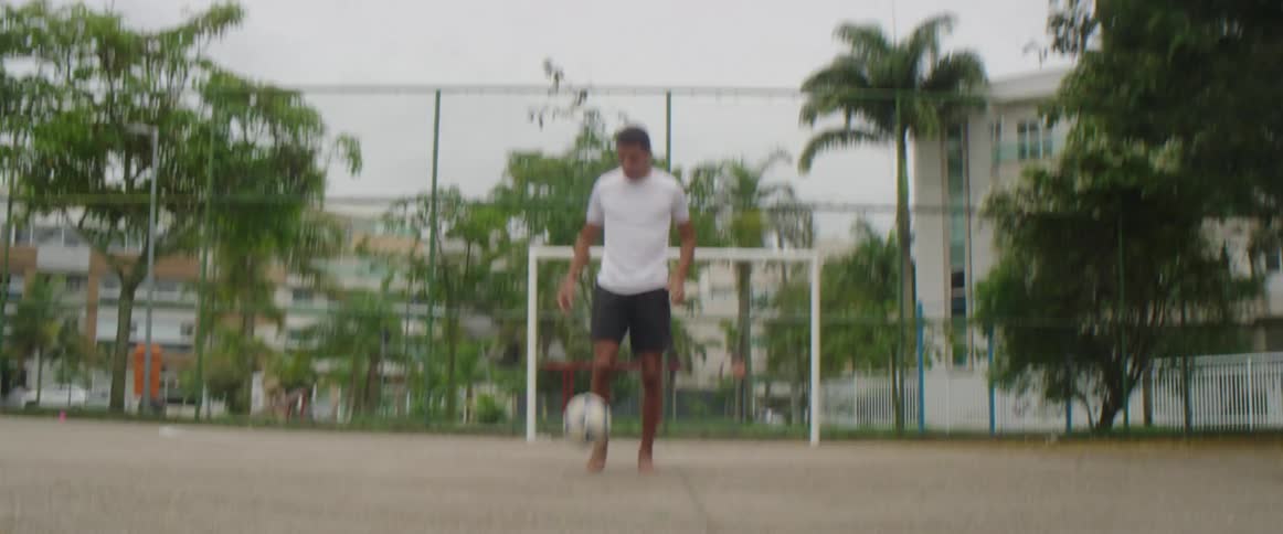 A boy is playing soccer in spring by himself