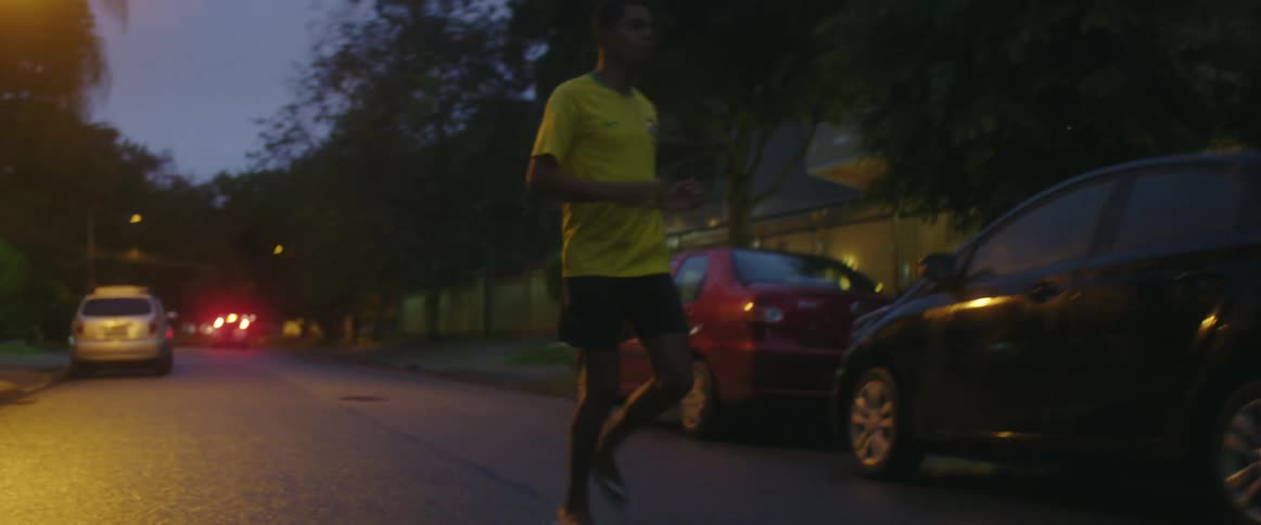 Three youths run along street passing soccer ball back and forth