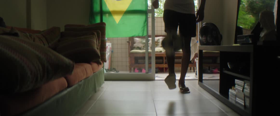 Man dribbles soccer ball standing in living room near television