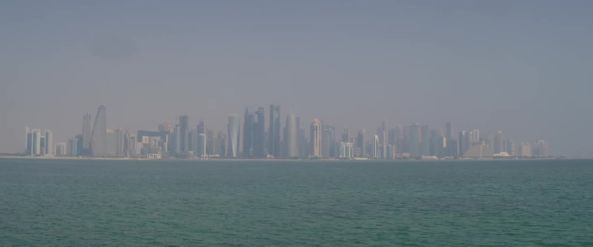 Ocean waves flow along surface as fog covers city on the horizon