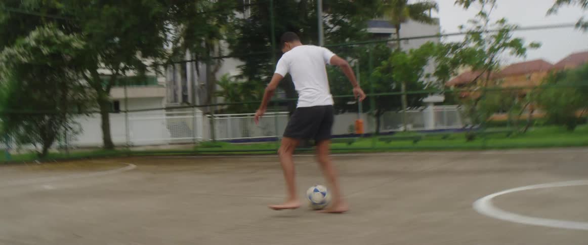 A man is playing soccer by himself in spring