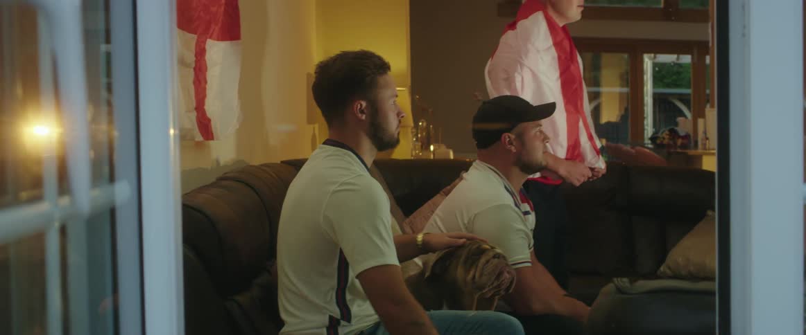 Group of friends with a pet dog watching a game at home
