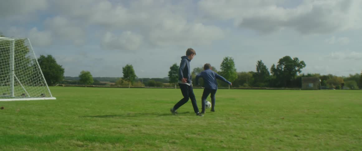 Two children are playing soccer in a field outdoors