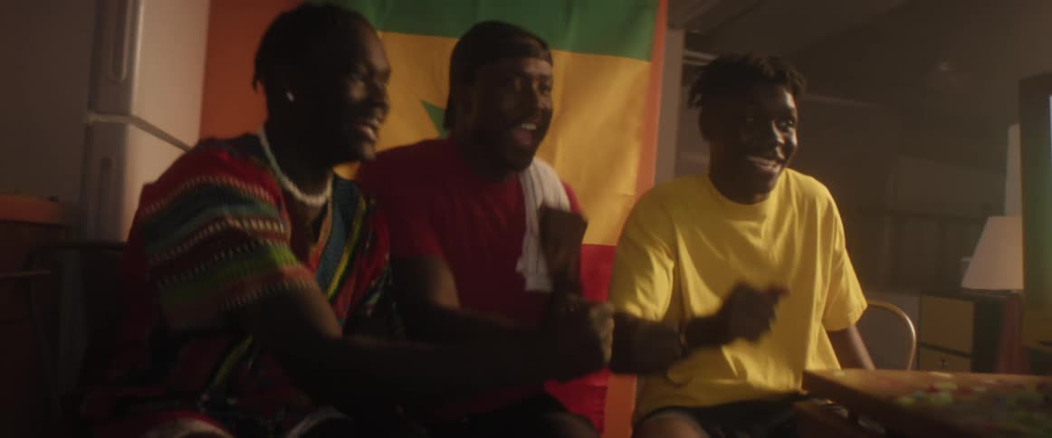 Group of friends sitting at home watching a game on television celebrate dancing