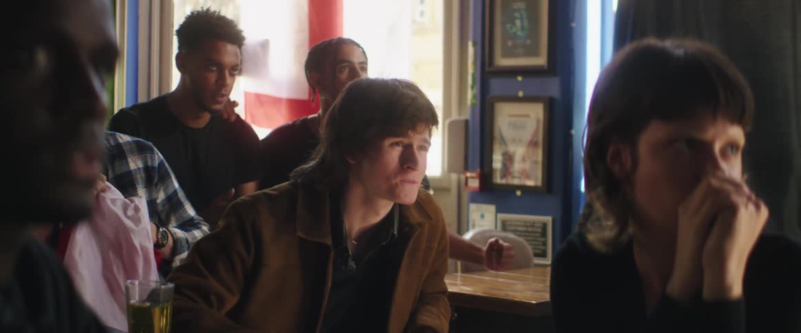 A group of people sit in a bar watching something and then they all cheer